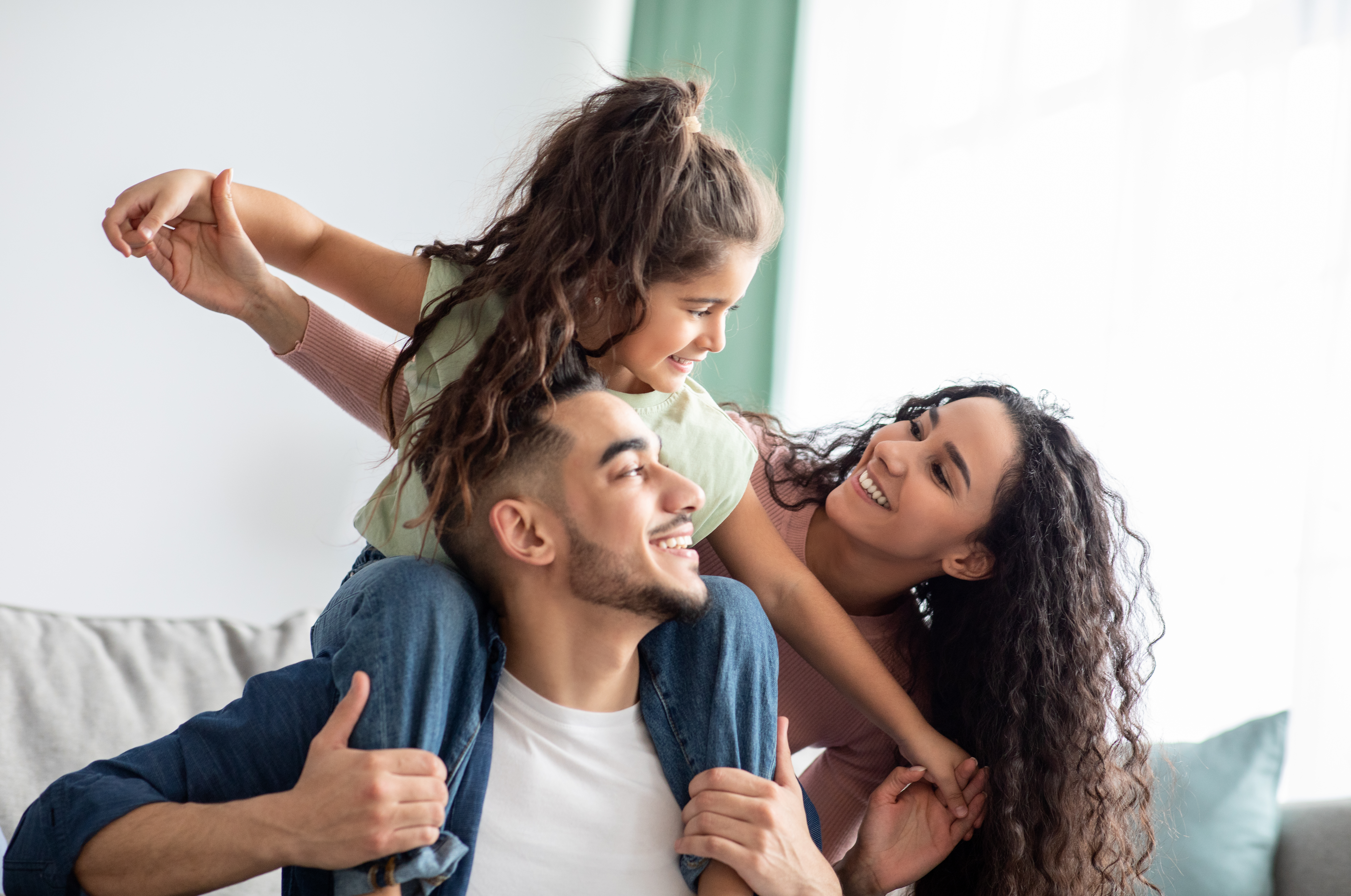 casal feliz brincando com a filha que está nos ombros do pai